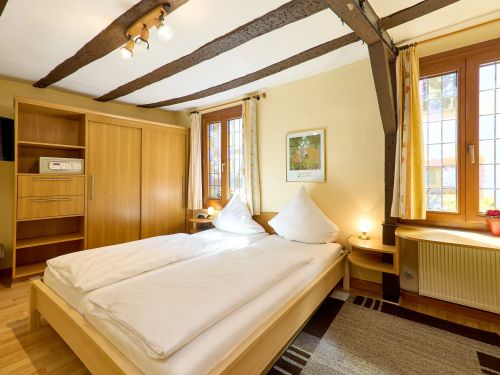 Hell eingerichtetes schlafzimmer mit holzmoebeln doppelbett und zwei fenstern mit gelben gardinen