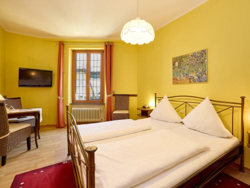 Gemütliches Schlafzimmer mit gelben Wänden Doppelbett rotem Teppich und einem kleinen Tisch mit Stühlen