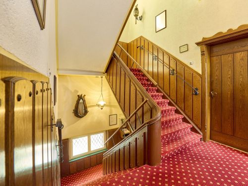 Treppenhaus mit rotem gemustertem Teppich holzverkleideten Wanden und metallgelender in einem gebaude innenraum