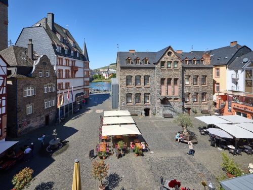 Historische Altstadt mit Fachwerkhäusern gepflastertem Platz und Sitzbereichen bei sonnigem Wetter am Flussufer